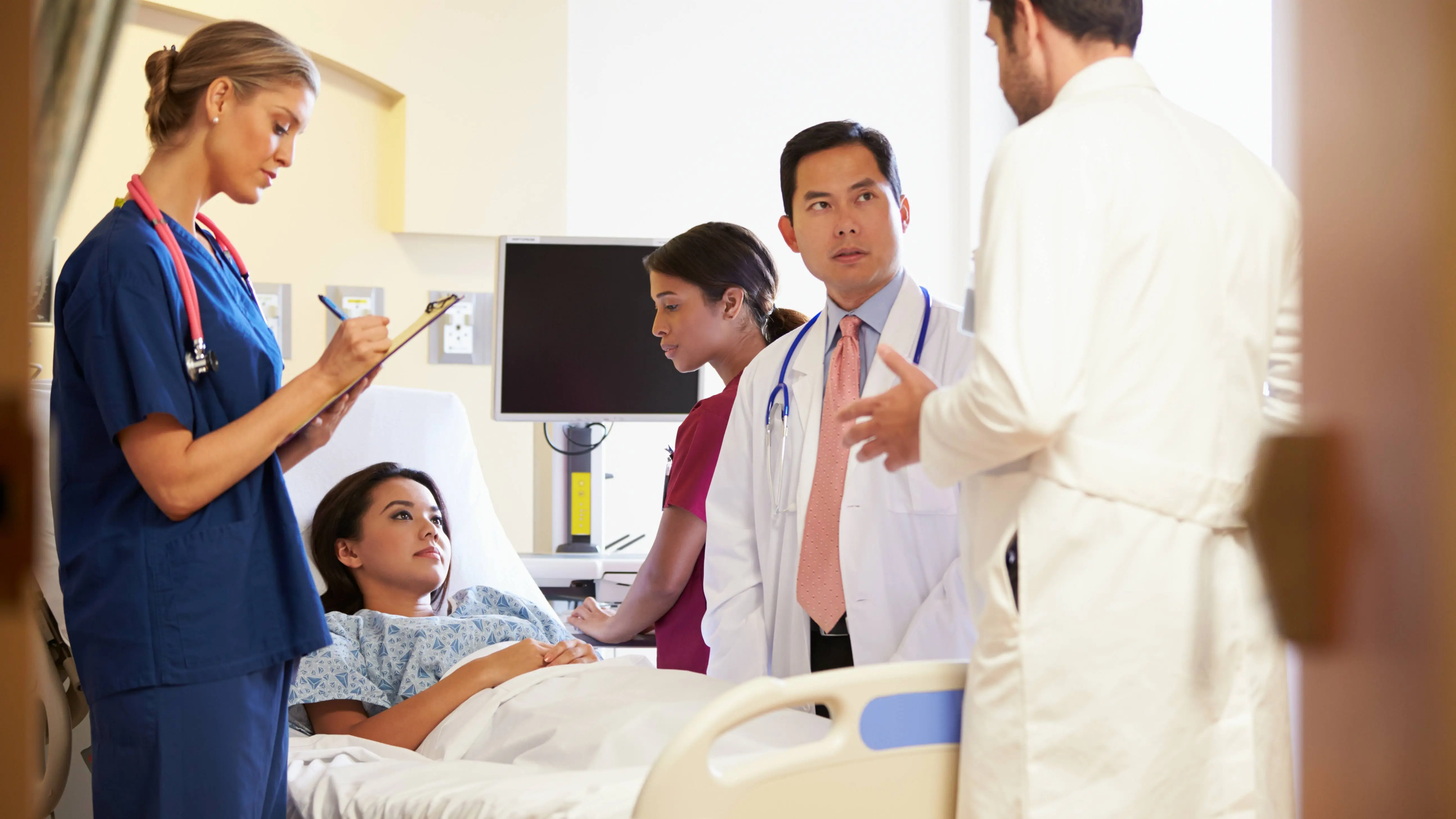 Medical-Team-Meeting-Around-Female-Patient-In-Hospital-Room_shutterstock_168812597_16x9